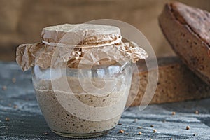 Rye sourdough in glass jar and loaf of whole grain bread, yeast-free leaven starter for handmade organic bread