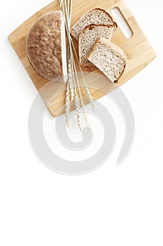 Rye and wheat bread. A loaf of bread on a cutting board with ears of wheat. Food. Top view