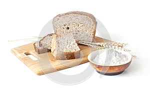 Rye and wheat bread. A loaf of bread on a cutting board with ears of wheat and a handful of wheat flour