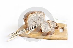 Rye and wheat bread. A loaf of bread on a cutting board with ears of wheat and a handful of wheat flour. Food