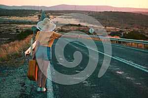 20s age One woman with a straw hat hitchhiking by the country roadside