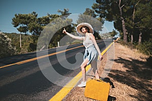 20s age One woman with a straw hat hitchhiking by the country roadside