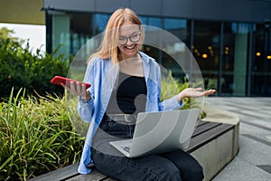 Frustrated business woman received bad news in e-mail on mobile phone while sits outside company near copy space