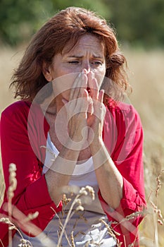 50s brunette woman having pollen allergies in field