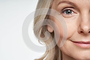 50s mid aged woman looking at camera. Anti age skin care. Half face crop