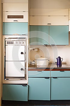 !960s Retrofitted blue kitchen in disrepair with electric oven. photo