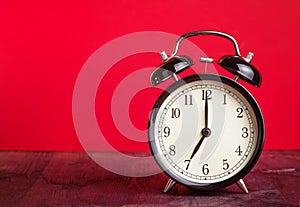 It`s seven o`clock already, time to wake up for love, vintage old black metallic alarm clock on red background