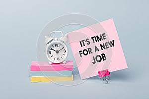 IT`S TIME FOR A NEW JOB - concept of text on pink sticky note. Closeup of a personal agenda. Alarm clock and colorful stickers