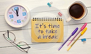 It`s time to take a break - an inscription on a notebook on a table with a clock and office supplies