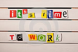 It's time to work - written with color magazine letter clippings on wooden board. Concept image