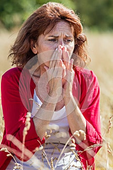 50s woman sneezing for rhinitis,allergies or hay fever