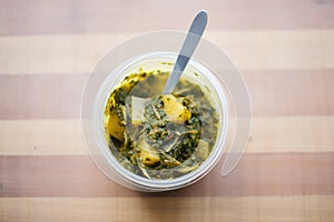 saag aloo in a takeout container with a fork photo