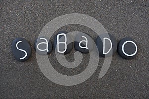 Sabado, seventh day of the week in portuguese language composed with black colored stone letters over black volcanic sand photo