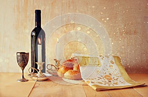 Sabbath image. challah bread and candelas on wooden table. glitter overlay