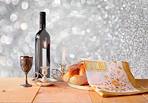 Sabbath image. challah bread and candelas on wooden table. glitter overlay