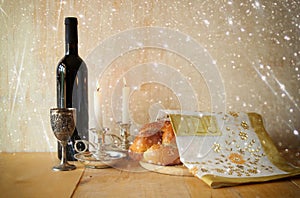 Sabbath image. challah bread and candelas on wooden table. glitter overlay