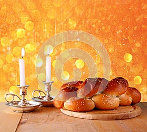 Sabbath image. challah bread and candelas on wooden table. glitter overlay