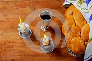 Sabbath Silver kiddush cup, crystal candlesticks with lit candles, and challah challahs