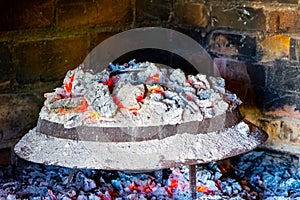 Sac, metalic lid covered by ashes and live coals