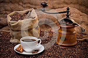 Sack of coffee beans, white cup and coffee grinder