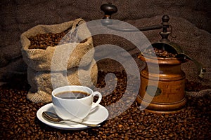 Sack of coffee beans, white cup and coffee grinder