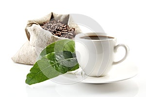 Sack full of coffee beans with green leaves and coffee cup photo