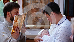 The sacrament of baptism. Christening the baby. Child, priest and godfather