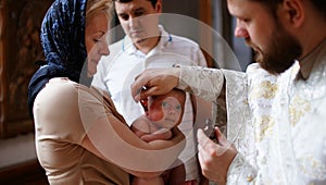 The sacrament of baptism. Christening the baby. Child, priest and godfather