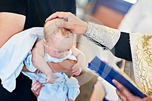 The sacrament of baptism. Newborn baby during christening and chrismation