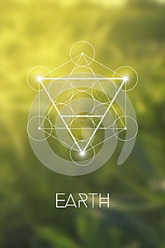 Sacred geometry Earth element symbol inside Metatron Cube and Flower of Life in front of natural blurry background