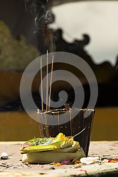 Sacred incense, religion offering in traditional balinese temple of Lempuyang on Bali, vertical. Incense sticks smoke, wicker.