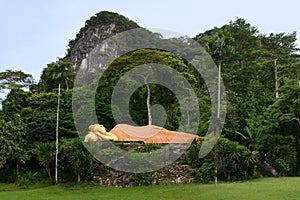 Sacred reclining Buddha statue in jungle forest. Krabi province, Thailand.