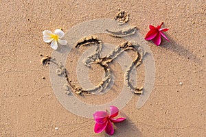 The sacred syllable om with frangipani flowers on the sand photo