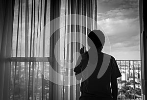 Sad adult Asian woman looking out of window and thinking. Stressed and depressed young woman. Despair women with long hair photo