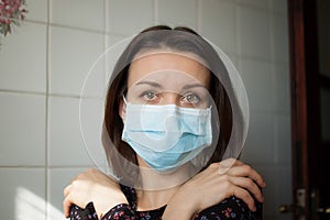 Sad adult girl is restricted at home because of the pandemia of Coronavirus Covid-19 and self-isolation. Woman is at the