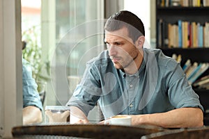 Sad adult man looking down in a coffee shop