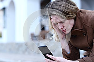 Sad adult woman reading bad news on mobile phone