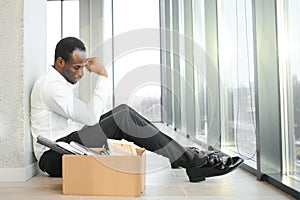 Sad african american businessman sitting on office building, man in business suit bankrupt fired from job, boss lost