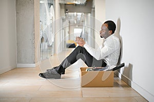 Sad african american businessman sitting on office building, man in business suit bankrupt fired from job, boss lost