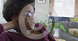 Sad african american teenage girl sitting on sofa in living room