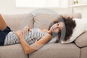Sad african-american woman on couch at home