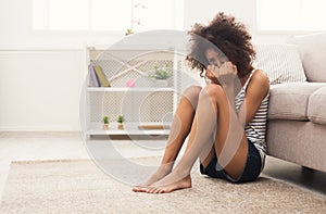 Sad african-american woman on floor at home