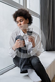 sad african american woman holding glass