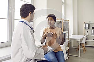 Sad African-American woman seeing doctor and telling him about pain in her chest