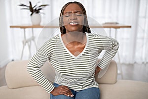 Sad african american woman touching back, have pain