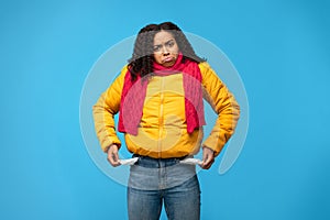 Sad African Woman Showing Empty Pockets Standing Over Blue Background