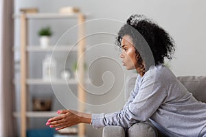 Sad african young woman feeling disappointed sitting alone at home