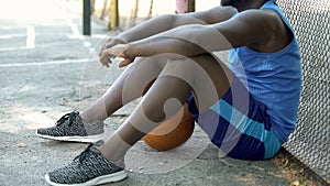 Sad Afro-American basketball player sitting on ground, lack of motivation