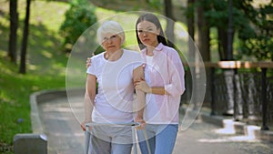 Sad aged patient walking frame and daughter looking camera, social insecurity