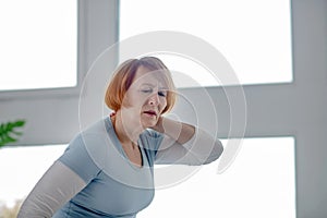 Sad aged woman suffering from pain in her muscles